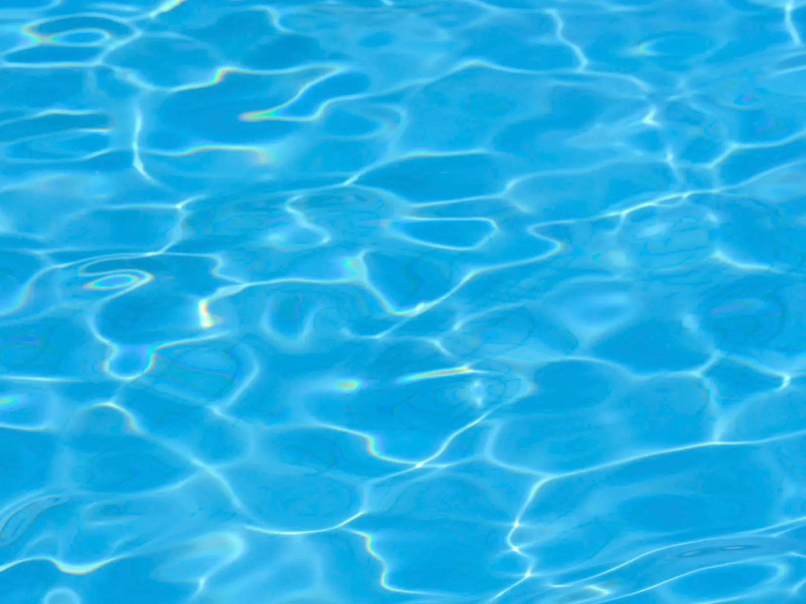 Sunlight rippling across clear blue swimming pool water